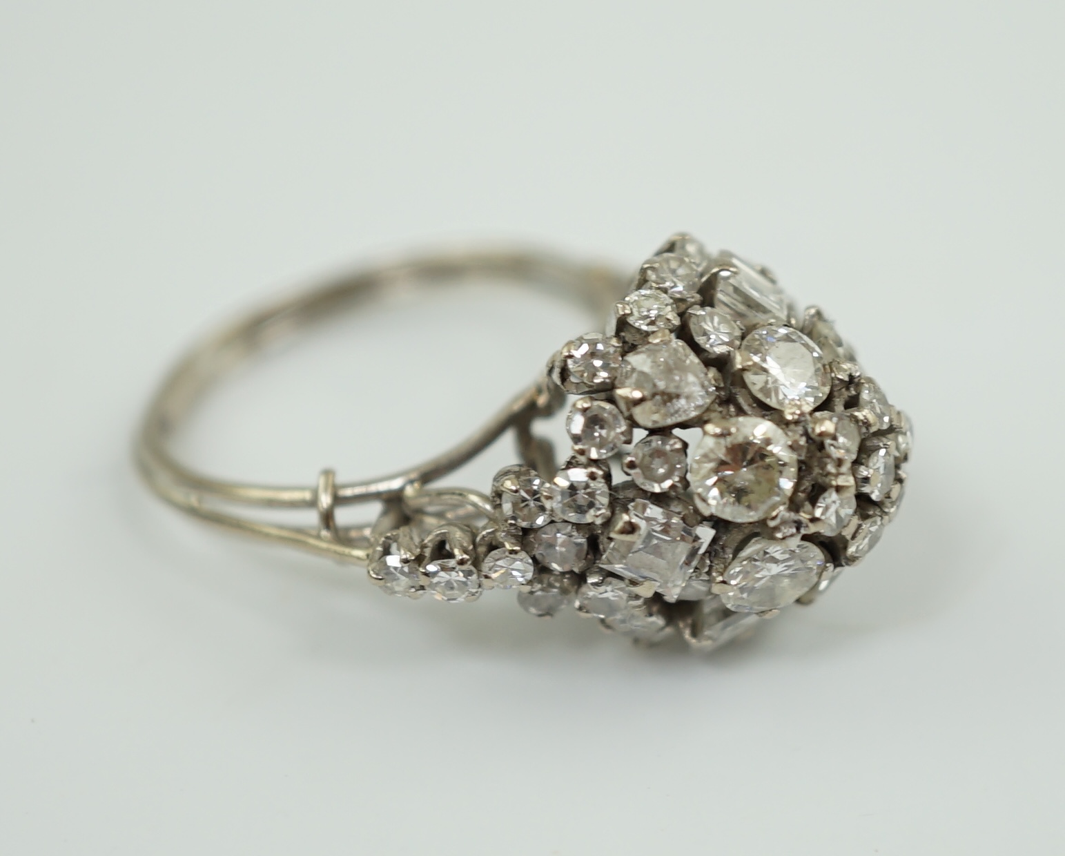 A mid 20th century platinum? and diamond cluster set dome shaped dress ring, with diamond set shoulders